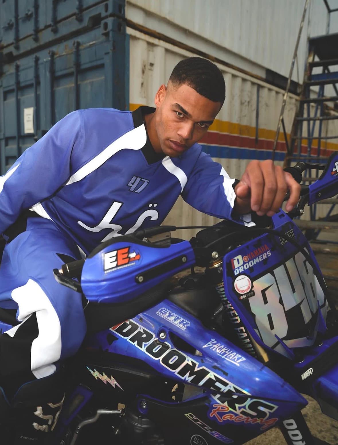 Man in blue and white motocross gear sits on a blue Yamaha dirt bike.